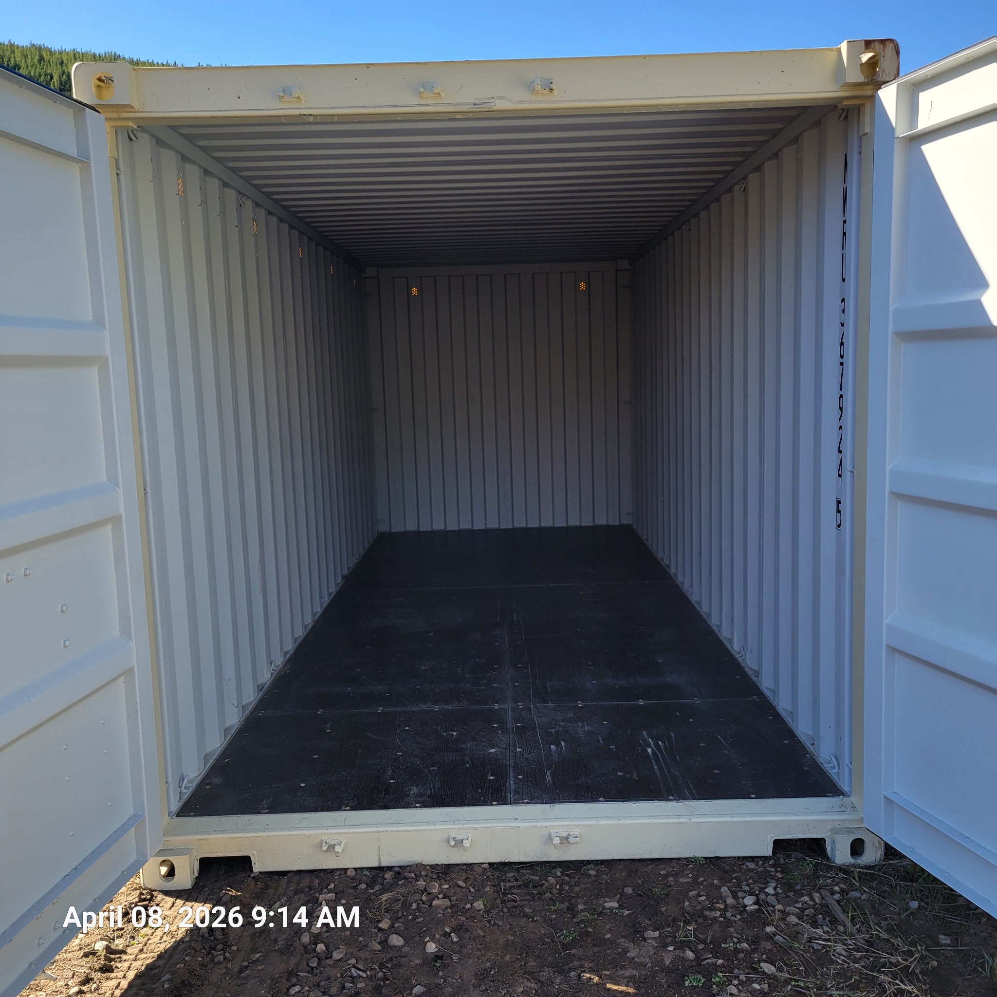 Interior of a 20 ft standard One-Trip container, clean black composite flooring, white corrugated steel walls, doors open