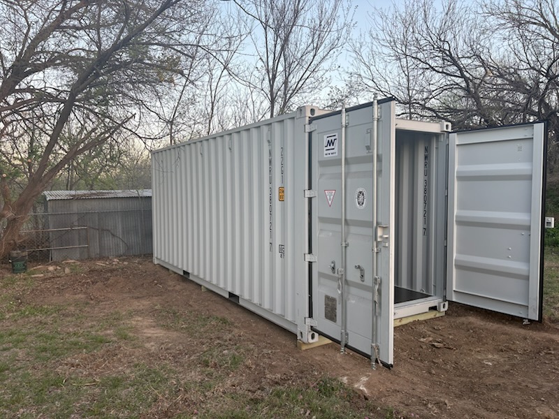 20 ft standard One-Trip container, light grey factory paint, side and door end visible, unit ID NMOU380721 and ISO code 22G1, residential delivery site