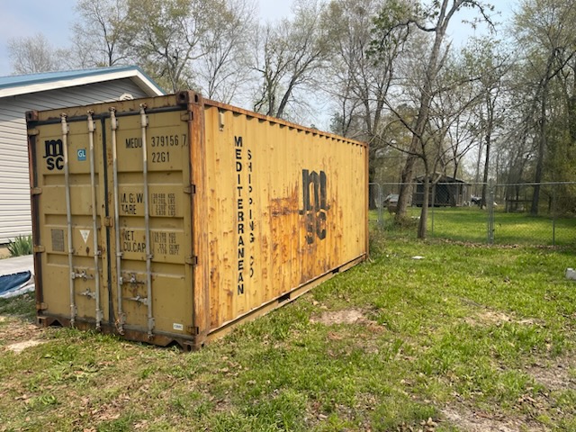 20 ft WWT shipping container, MSC Mediterranean Shipping Company livery, yellow-tan paint with surface rust, delivered to residential property in the Southeast