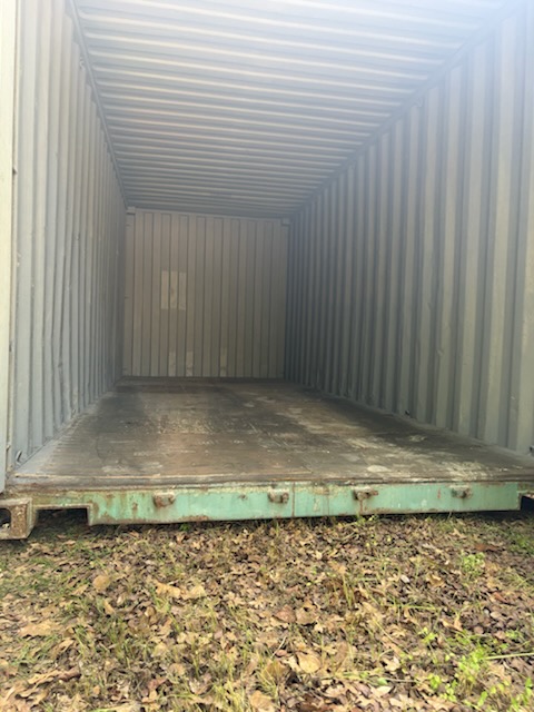 Interior of a 20 ft WWT shipping container, clean corrugated walls, worn wood flooring, no visible damage or holes