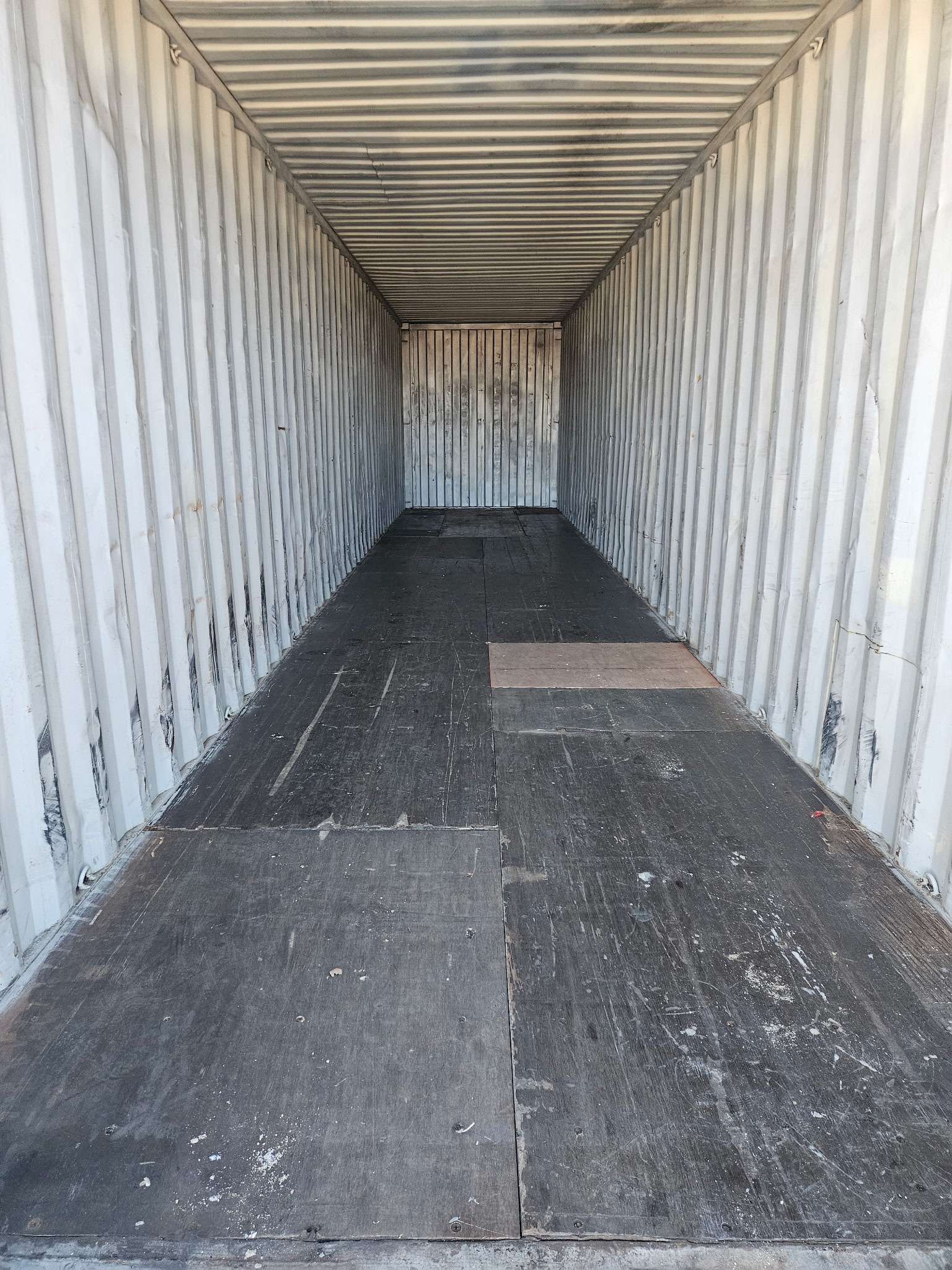 Interior of a 40 ft High-Cube Cargo Worthy container, looking toward front wall, steel floor panels and corrugated walls visible