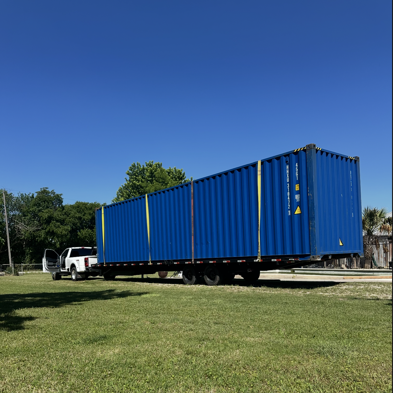 Blue 40 ft High-Cube Premium Multi-Trip shipping container on a trailer in a grassy setting