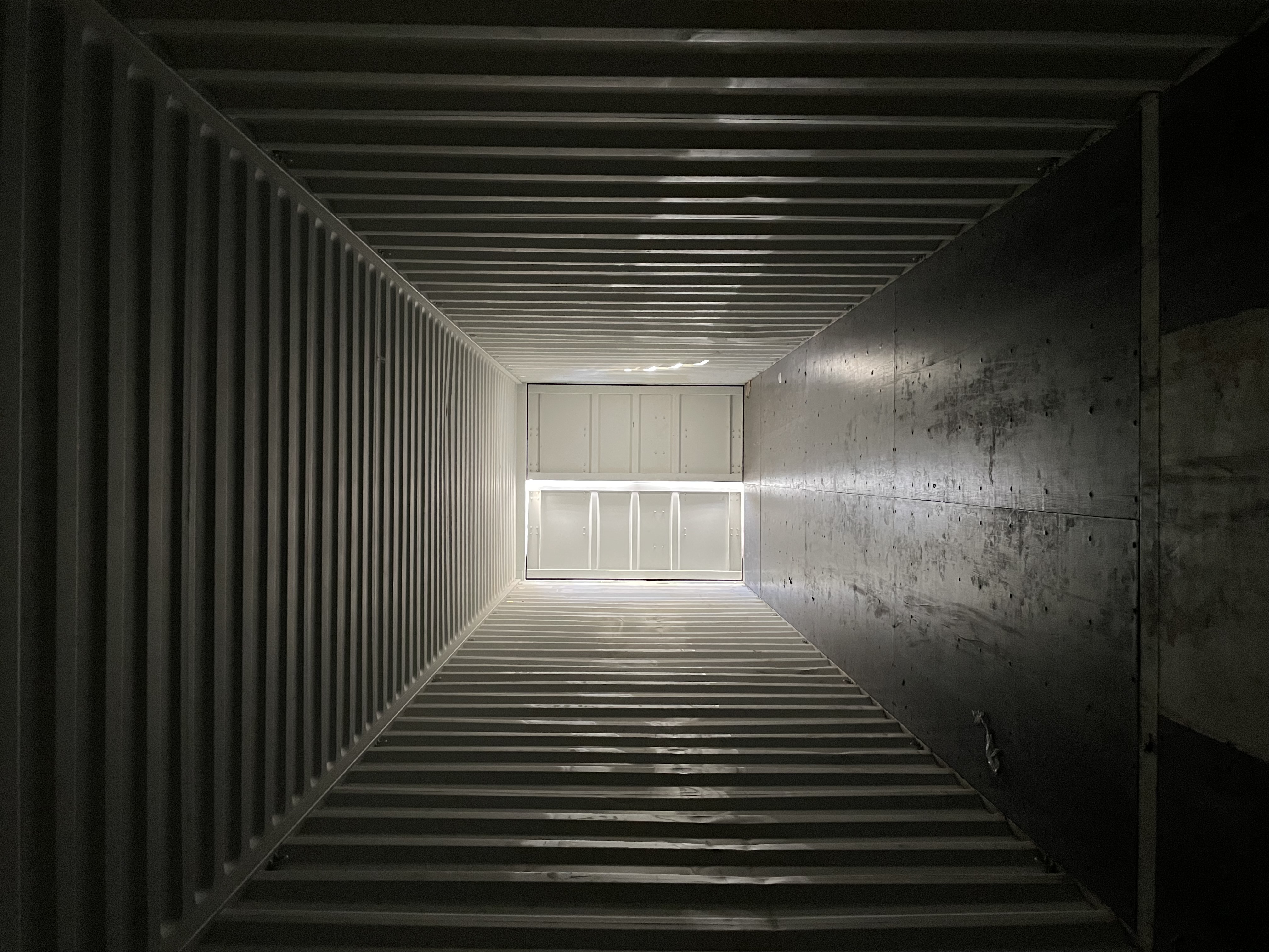 Interior of a Premium Multi-Trip shipping container viewed from the open doors, with intact walls, ceiling bows, and floor